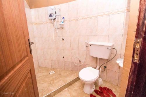 een badkamer met een toilet en een telefoon aan de muur bij Governors Club in Entebbe