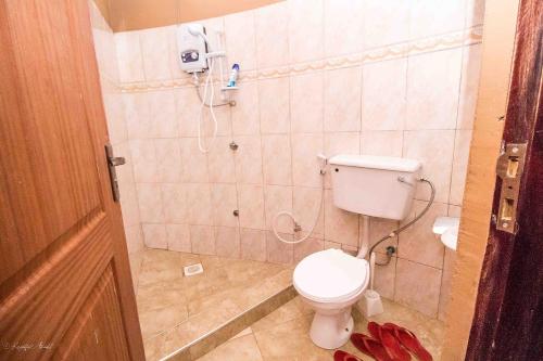 a bathroom with a toilet and a phone on the wall at Governors Club in Entebbe