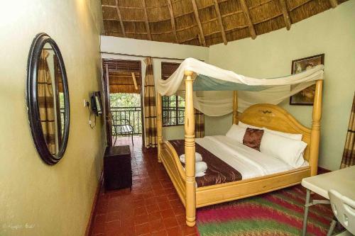 een slaapkamer met een hemelbed en een spiegel bij Governors Club in Entebbe