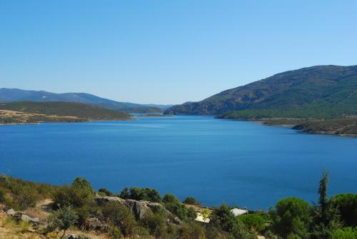 vistas a un lago con montañas en el fondo en Alojamientos La Dehesa, en El Berrueco