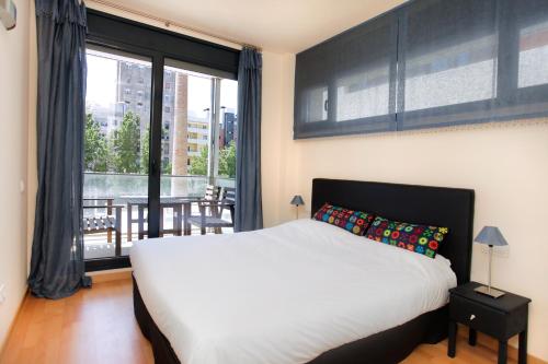 a bedroom with a white bed and a large window at 1215 - Ciutadella Pretty Apartment in Barcelona