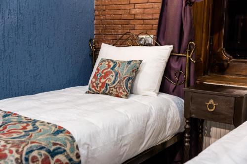 a bed with white sheets and a pillow on it at Tiflis Inn Boutique Hotel in Tbilisi City