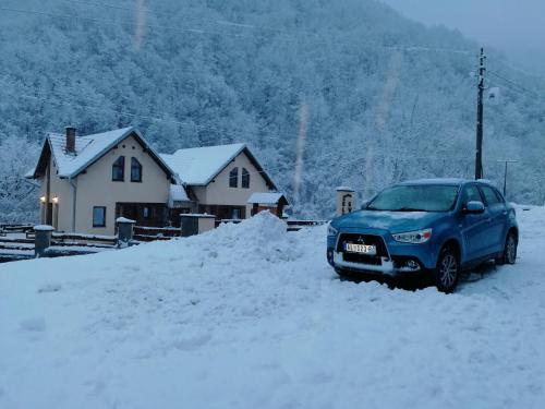a blue car parked in the snow in front of a house at Lodge Zeleni svet in Crni Vrh