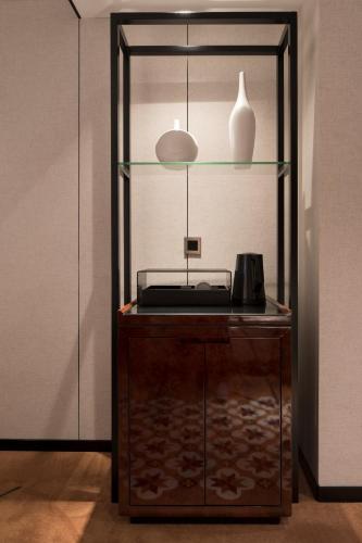 a glass display case with a phone and a vase on it at Paco Hotel GuangZhou Zoo Metro Branch Free shuttle bus during the Canton Fair in Guangzhou