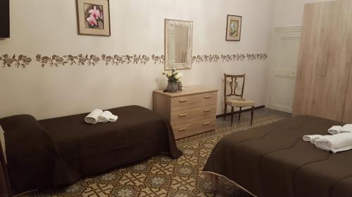 a bedroom with two beds and a chair and a dresser at Sweet Home Cefalù in Cefalù