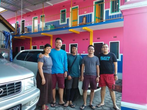 a group of people standing in front of a pink building at Homestay Lidiya in Banyuwangi