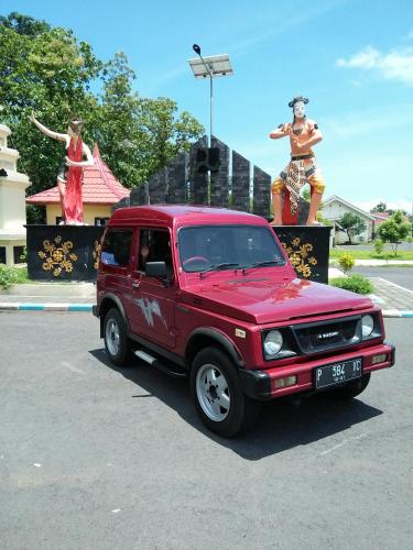 a red truck parked in front of a statue at Homestay Lidiya in Banyuwangi