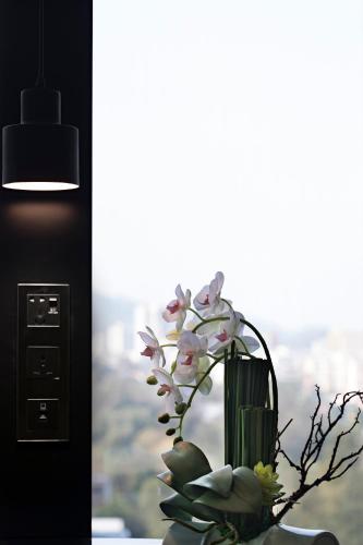 a vase with flowers in a room with a window at Paco Hotel GuangZhou Zoo Metro Branch Free shuttle bus during the Canton Fair in Guangzhou