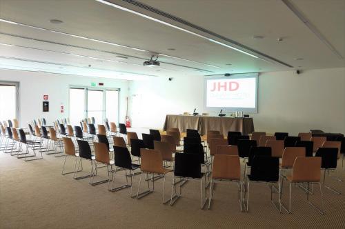 a conference room with a table and chairs and a screen at Aiden by Best Western JHD Dunant Hotel in Castiglione delle Stiviere