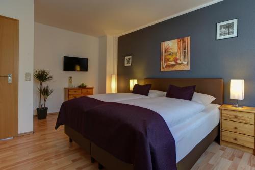 a bedroom with a large white bed with purple sheets at Boardinghouse Mundsburg in Hamburg