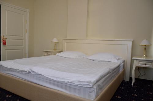 a bed with white sheets and pillows in a bedroom at Chateau Royal Hotel in Berezovka