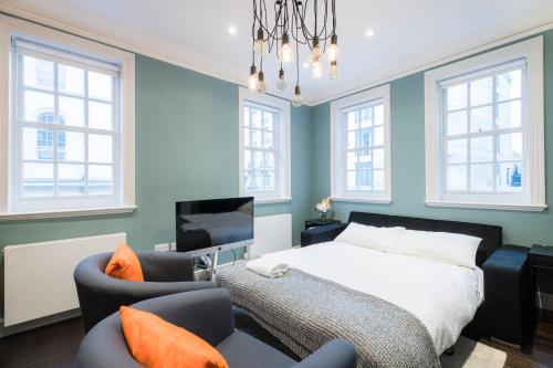 ロンドンにあるElegant 2 bed in Mayfair, next to Hyde Parkのベッドルーム1室(ベッド1台、椅子2脚、テレビ付)