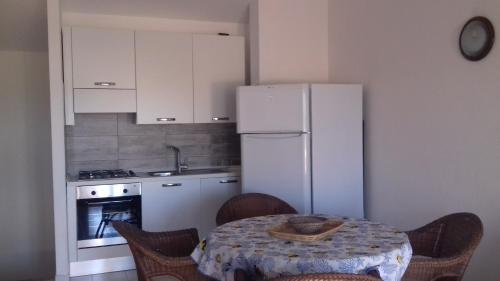 a kitchen with a table and a white refrigerator at Residenze Coda Cavallo in San Teodoro