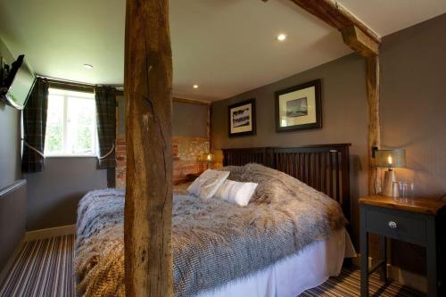 een slaapkamer met een groot bed met een houten frame bij The Woolpack Inn in Brown Candover