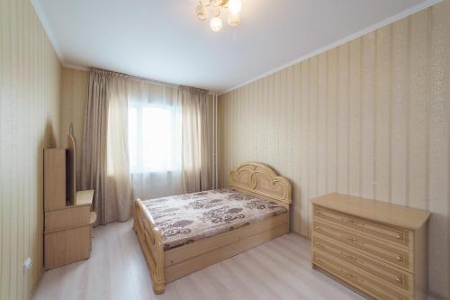a bedroom with a bed and a dresser and a window at Притомский, 13 in Kemerovo