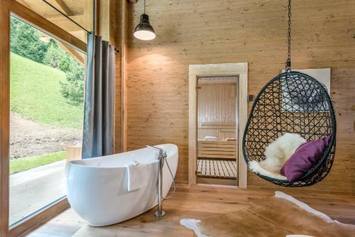 ein Badezimmer mit einem Schaukelstuhl und einer Badewanne in der Unterkunft LA SOA Chalets & Eventlodge in Schattwald