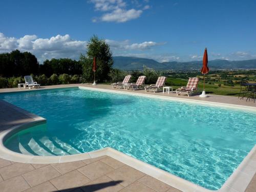 a large swimming pool with chairs and a view at Genius Loci Country Inn in Bevagna