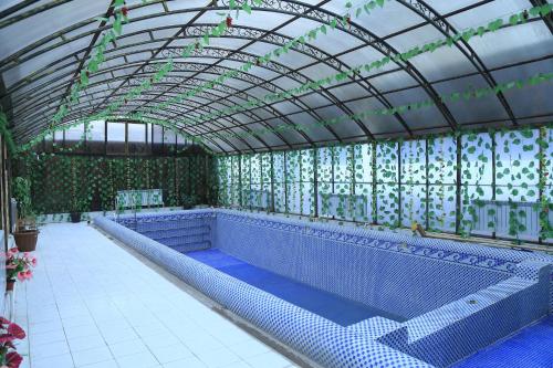 a large swimming pool with a glass roof and an indoor swimming poolvisor at Hotel Nurafshon Boutique in Bukhara