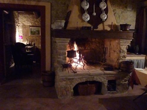 a stone fireplace in a living room with a fire at Genius Loci Country Inn in Bevagna