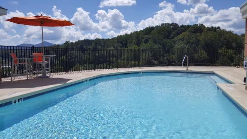 a swimming pool with an umbrella and a chair and an umbrella at Comfort Inn Sylva - Cullowhee in Dillsboro