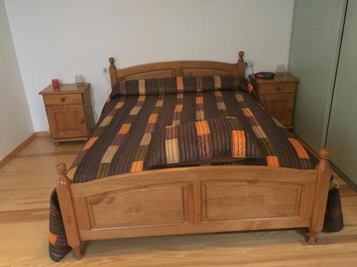 a wooden bed in a room with two night stands at Chambres à Nogaro in Nogaro