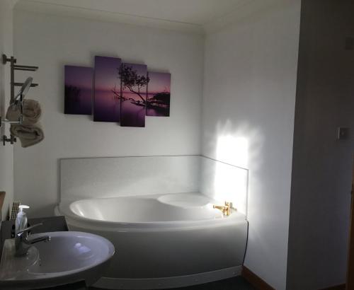 a white bathroom with a tub and a sink at House on the Falls in Portree