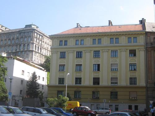a large yellow building with cars parked in a parking lot at Schieszl Apartments 1 in Budapest
