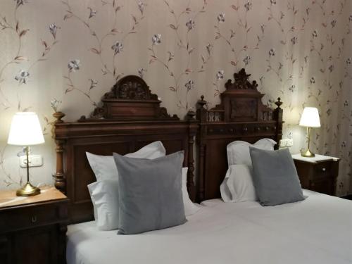 a bedroom with a bed with white pillows and floral wallpaper at Hotel El Xalet in Sitges