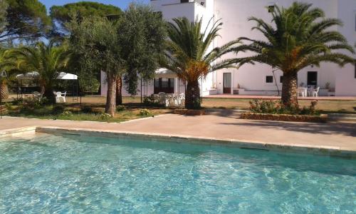 a swimming pool in front of a house with palm trees at Tenuta Afra in Squinzano