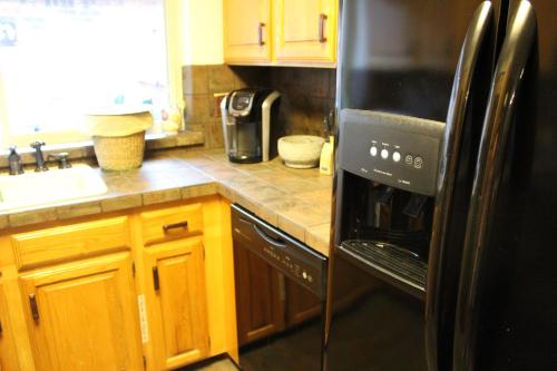 a kitchen with a black refrigerator and wooden cabinets at Comfy Cozy Affordable Home Away Home in Garland