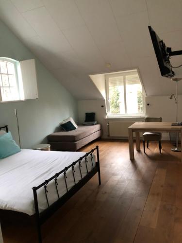 a bedroom with a bed and a couch and a table at Hotel De Hoefpoort in Gemert