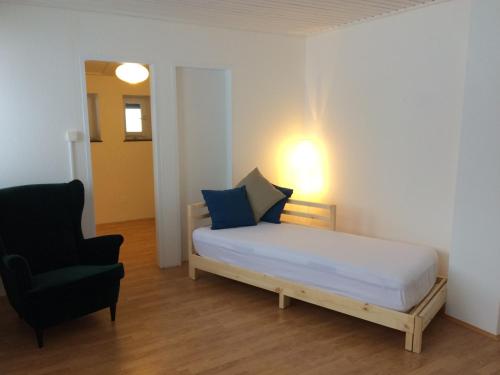 ein kleines Schlafzimmer mit einem Bett und einem Stuhl in der Unterkunft Apartement Postalm in Abtenau
