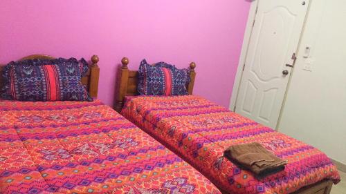a bedroom with two beds and a pink wall at Vanlisut Hotel Ngamwongwan in Nonthaburi