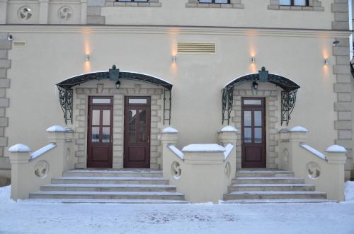 a building with two doors and stairs in the snow at Chateau Royal Hotel in Berezovka