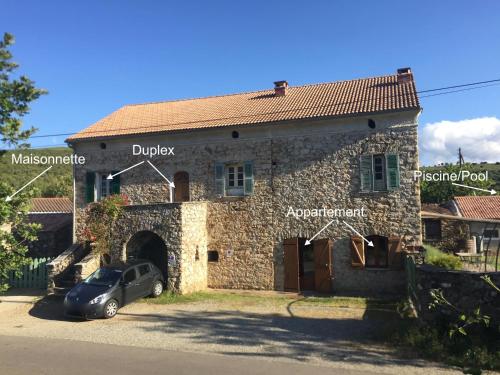 a stone house with a car parked in front of it at Appartements de Charme in Corte