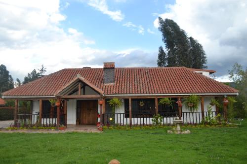 ein Haus mit einem roten Dach und einem Hof in der Unterkunft Cabaña la Chocolatera in Tibasosa