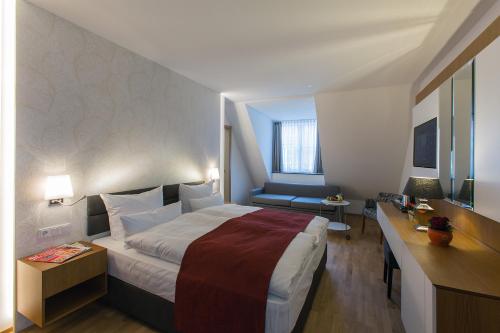 a hotel room with a large bed and a desk at Hotel am Schrannenplatz in Memmingen