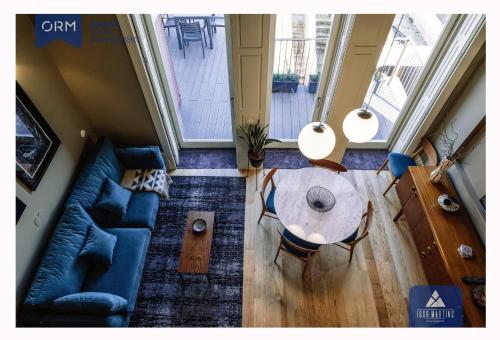 Una sala de estar con una mesa y un sofá azul. en ORM - Almada Terrace Apartment, en Oporto