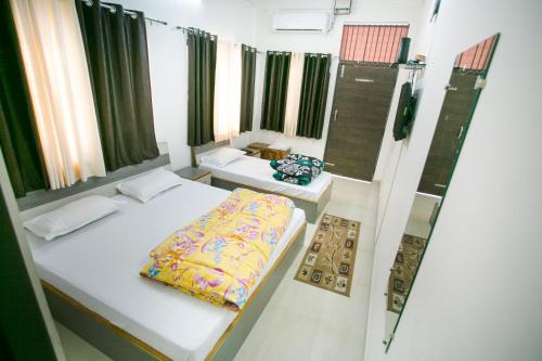德拉敦Hotel Shiv Kripa的小房间设有两张床和两张桌子