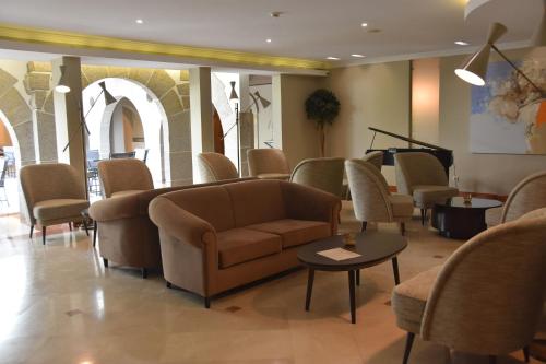 a waiting room with chairs and a couch and a piano at Hotel Suave Mar in Esposende