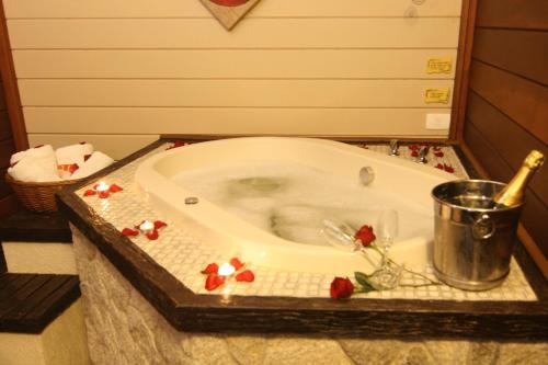 a bath tub with flowers around it in a bathroom at Pousada Varanda das Colinas in Monte Verde