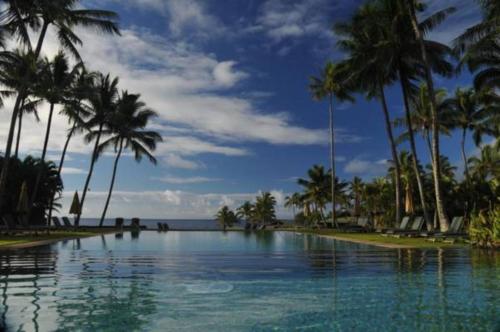 a swimming pool with palm trees and the ocean at Hana-Maui Resort, a Destination by Hyatt Residence in Hana