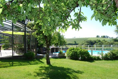 a tree in the yard of a house with a pool at Les Maisons de Concasty in Boisset