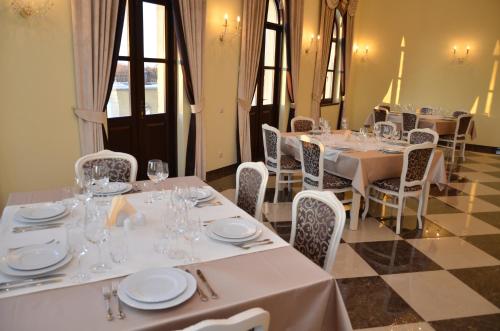 uma sala de jantar com mesas e cadeiras brancas em Chateau Royal Hotel em Berezovka