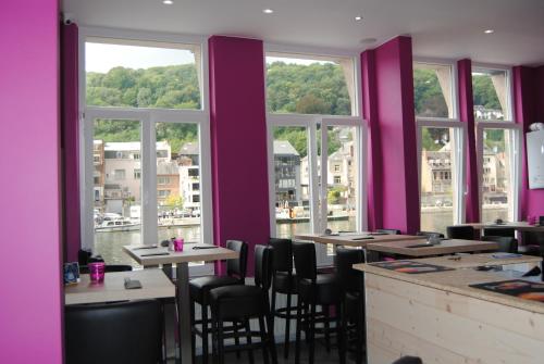 un restaurante con paredes moradas, mesas y ventanas en L'Inattendu "sur la croisette" Dinant centre, en Dinant