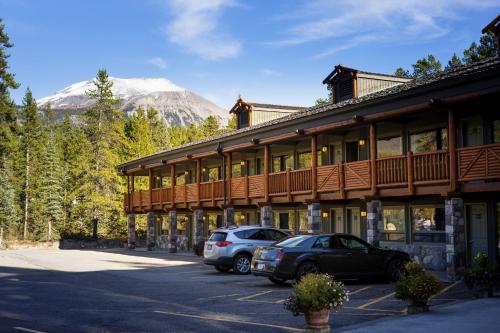 a building with cars parked in a parking lot with a mountain at Mountaineer Lodge in Lake Louise