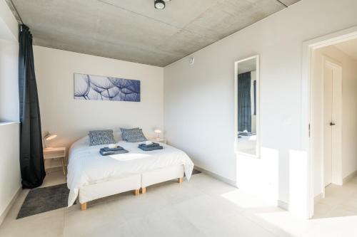 Una habitación blanca con una cama y una ventana en BeHome Dilbeek, en Dilbeek