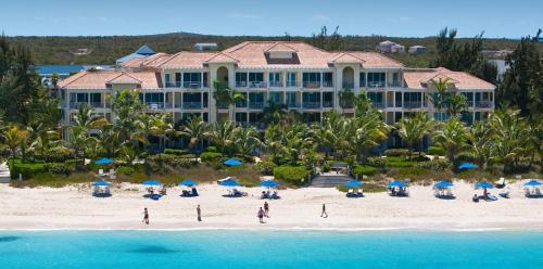 a resort on a beach with people on the beach at Villa Renaissance in Grace Bay