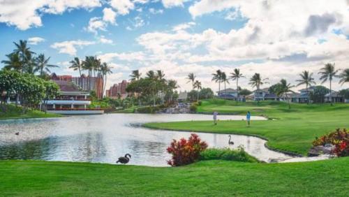 a golf course with a pond and palm trees at Four Seasons Resort Oahu at Ko Olina in Kapolei