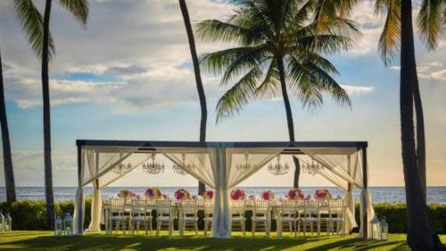 a wedding ceremony on the beach with palm trees at Four Seasons Resort Oahu at Ko Olina in Kapolei